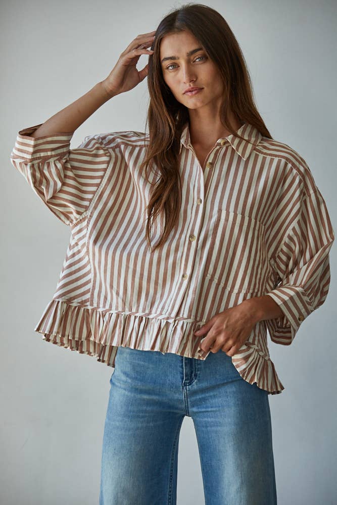 Woman wearing a striped blouse and blue jeans against a plain background