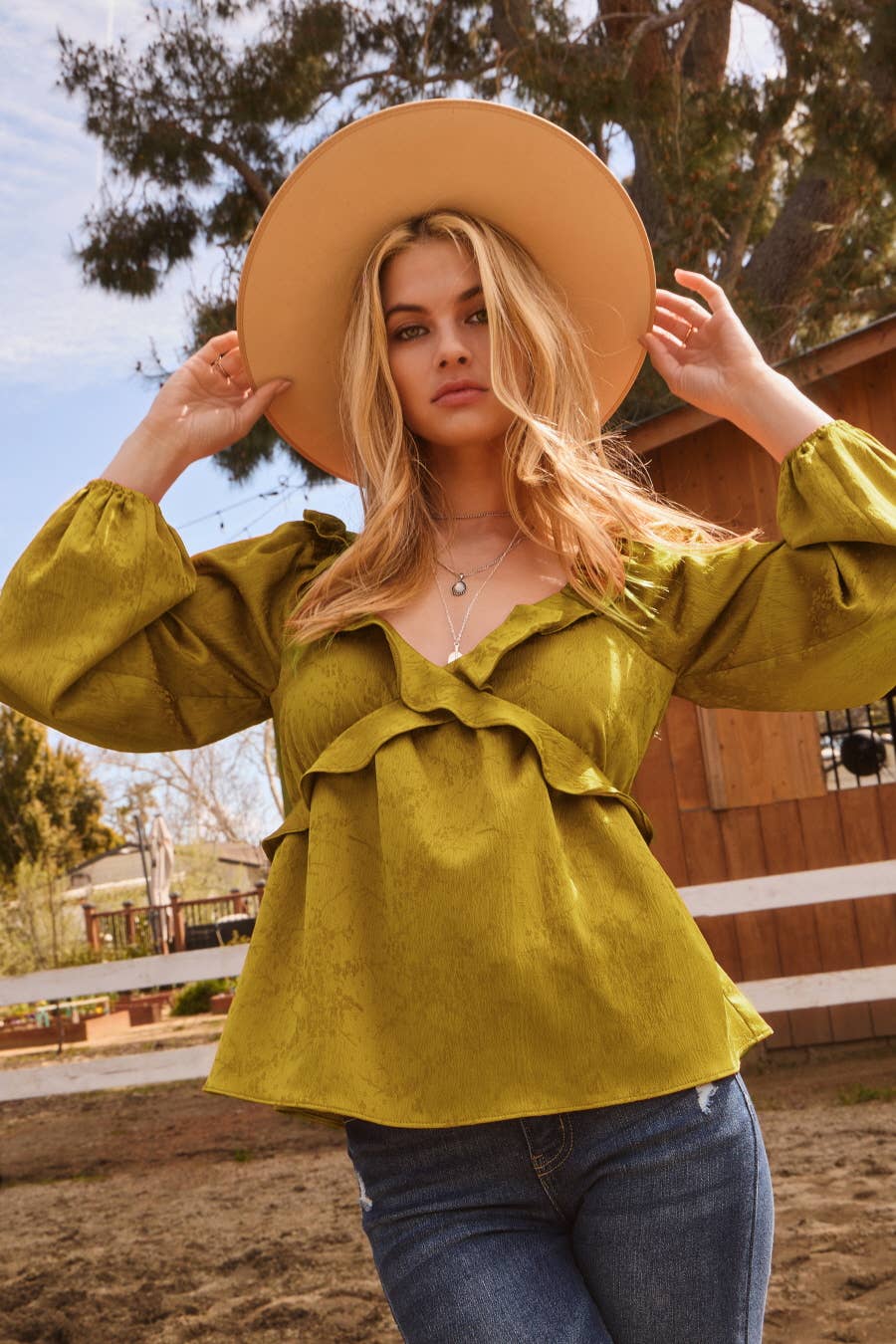 Woman wearing a yellow blouse and wide-brimmed hat outdoors
