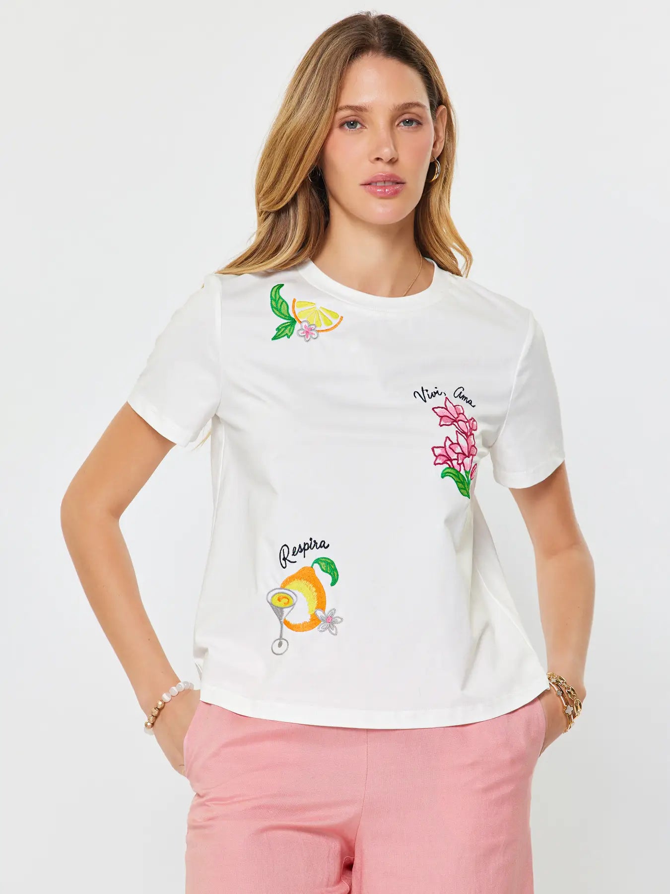 Woman wearing a white t-shirt with colorful graphics on a plain background