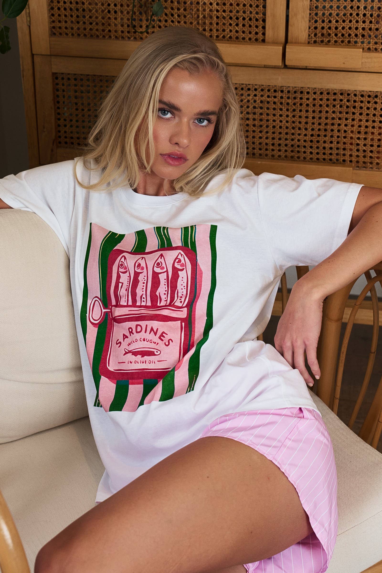 Woman wearing a white t-shirt with a graphic design sitting on a couch.
