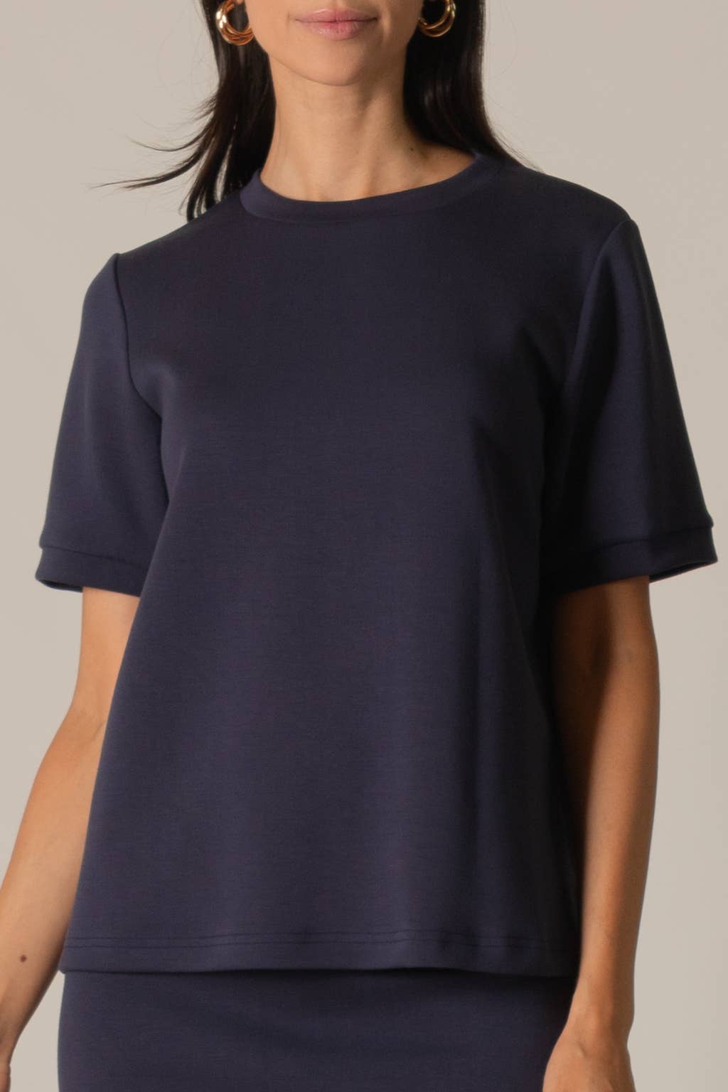 Navy blue t-shirt worn by a person on a neutral background