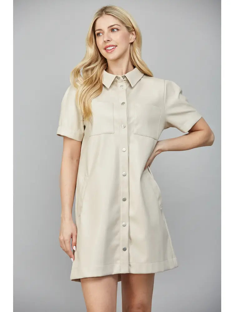 Woman wearing a beige shirt dress against a gray background