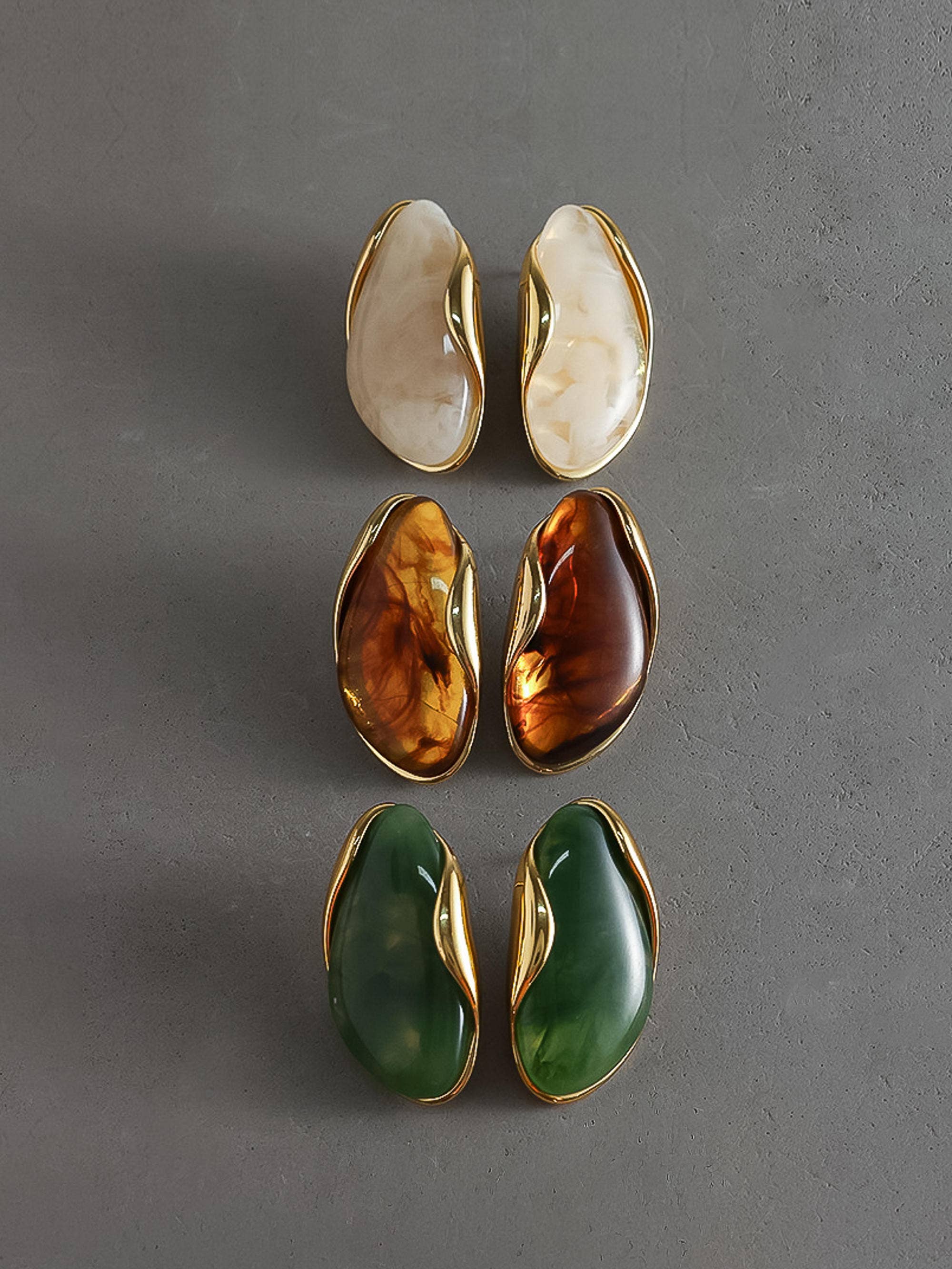 Set of four earrings with gold accents on a gray background