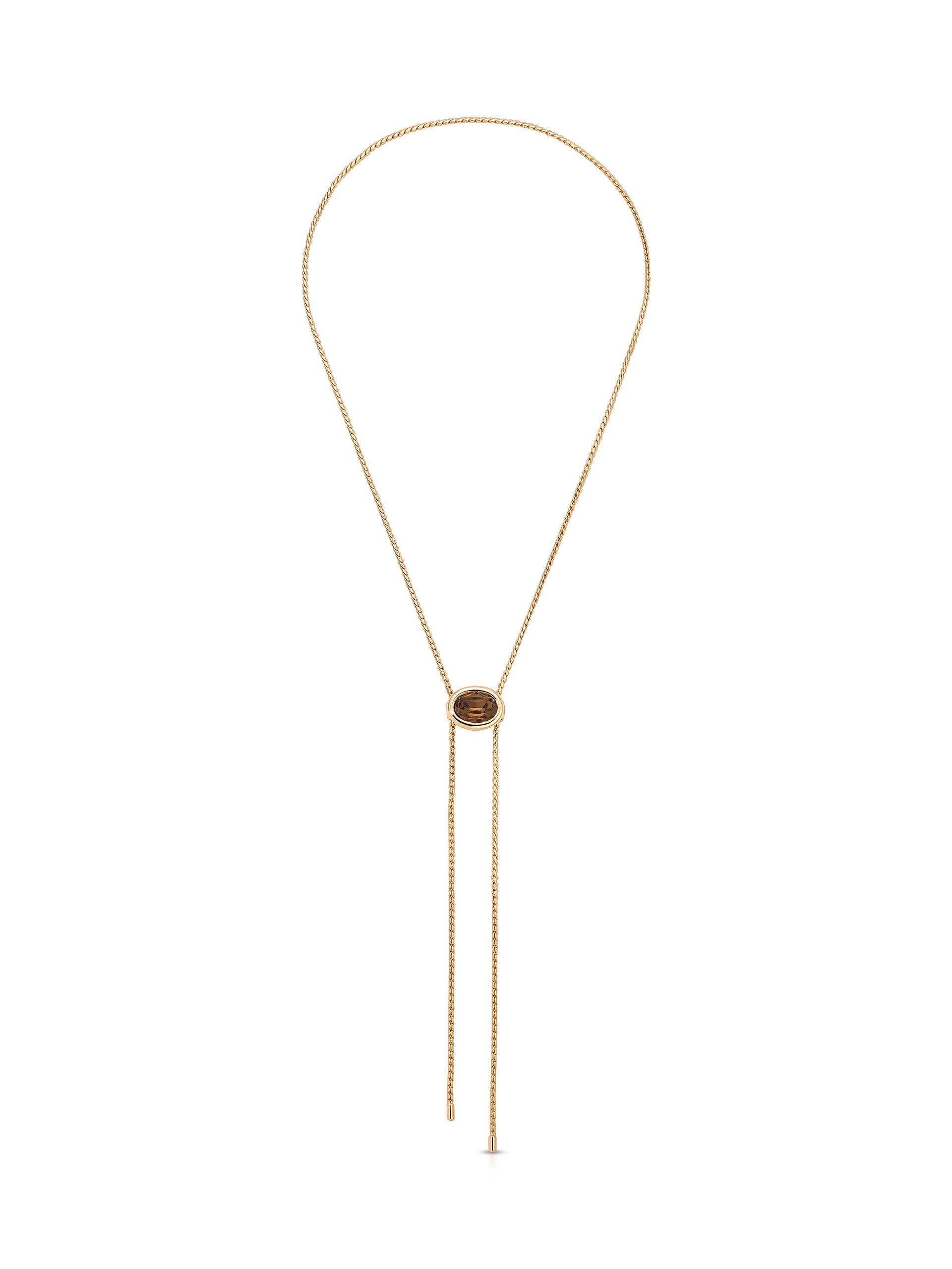 A delicate gold lariat necklace with a central oval medallion and two long dangling chains, displayed on a clean white background.