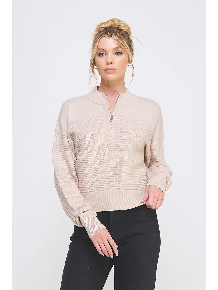 Woman wearing a beige zip-up sweater against a white background