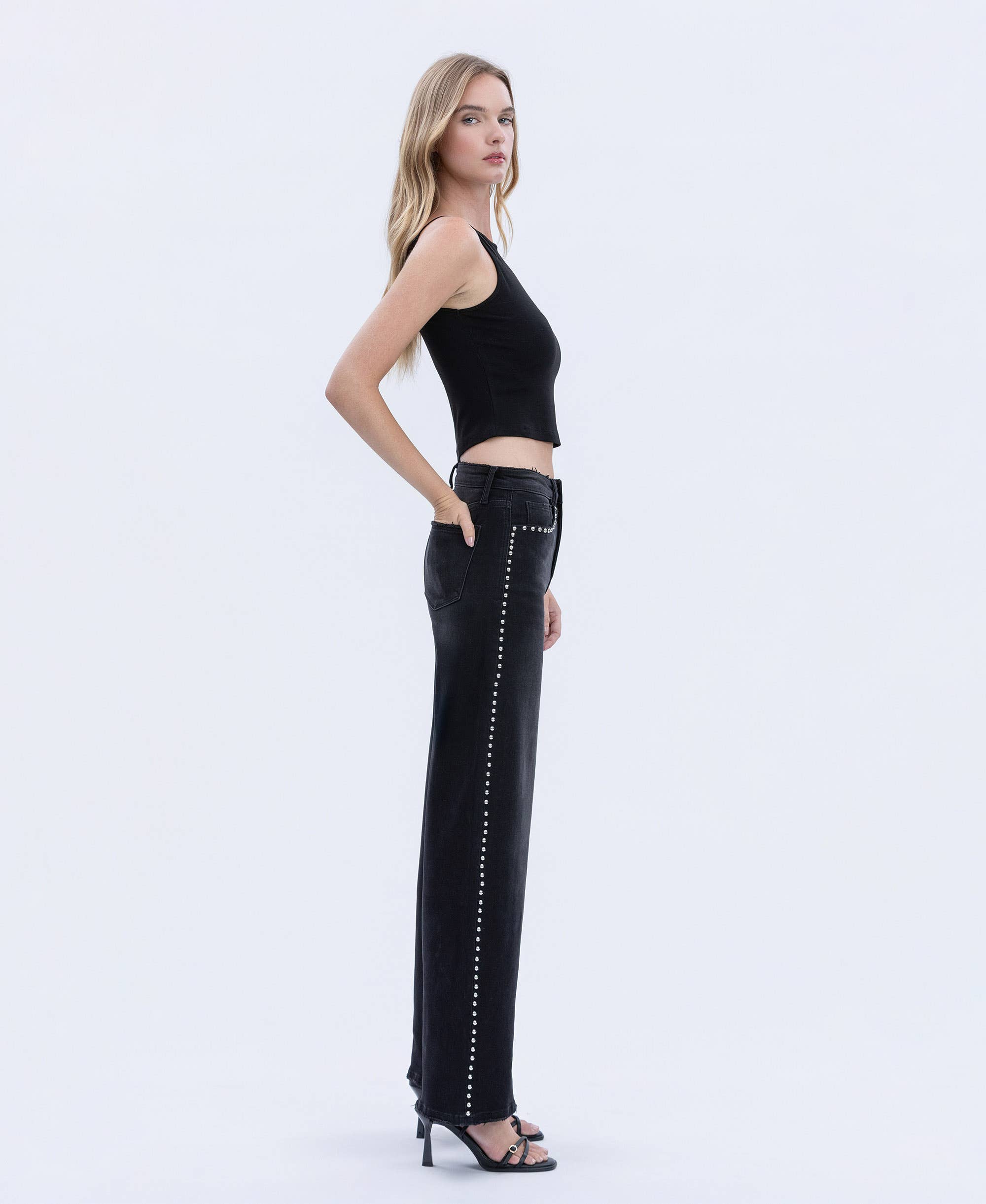 Woman wearing black studded pants on a white background