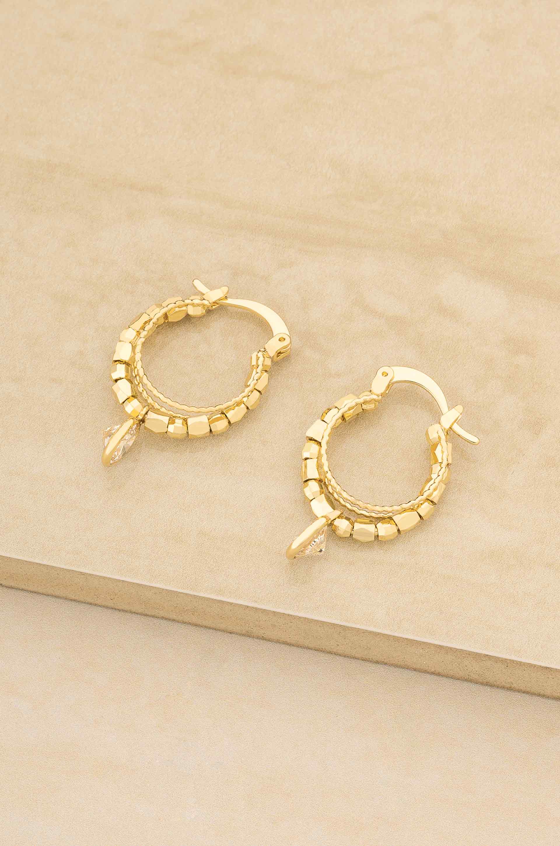 Gold hoop earrings on a beige surface