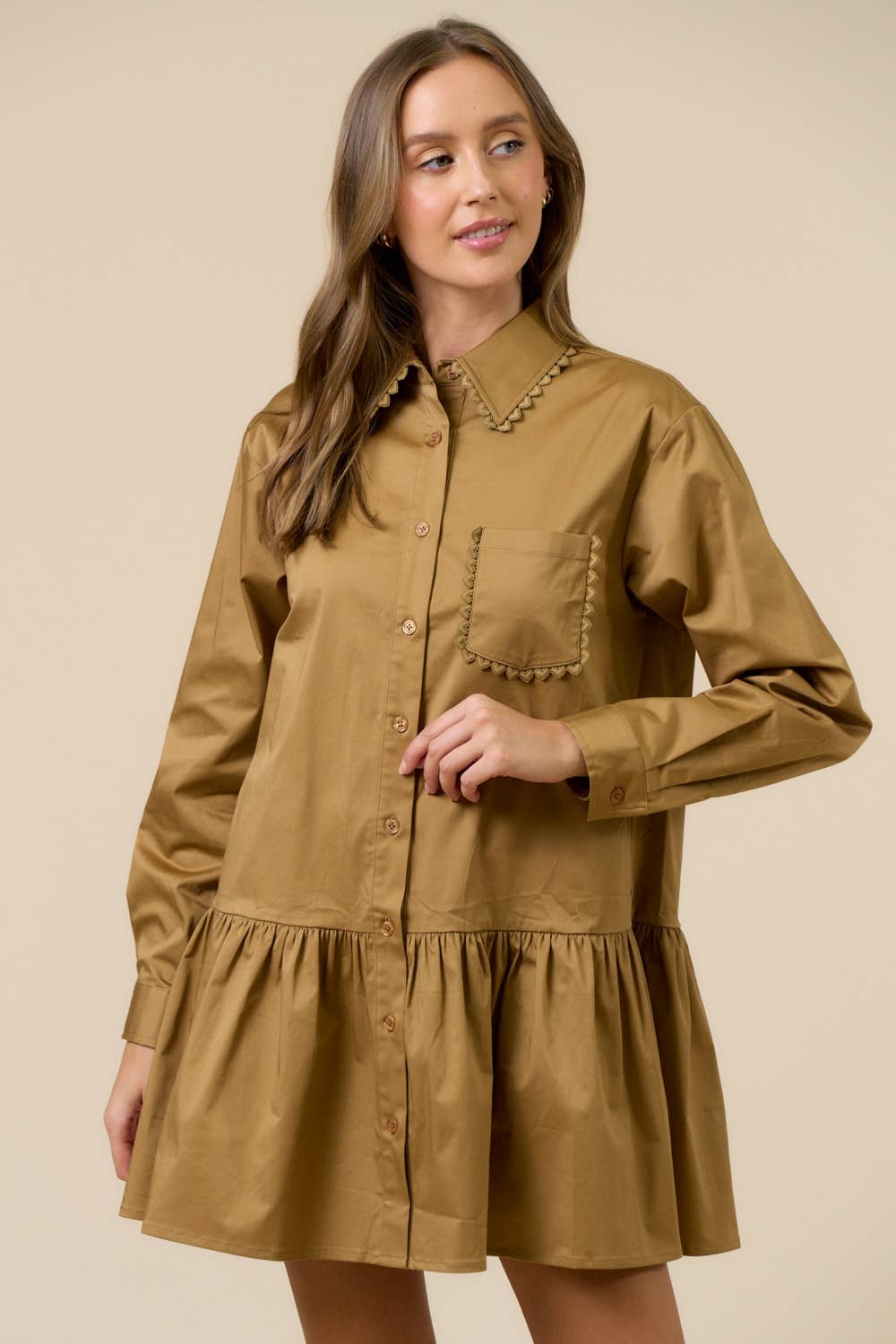 Woman wearing a brown dress with a collar against a beige background