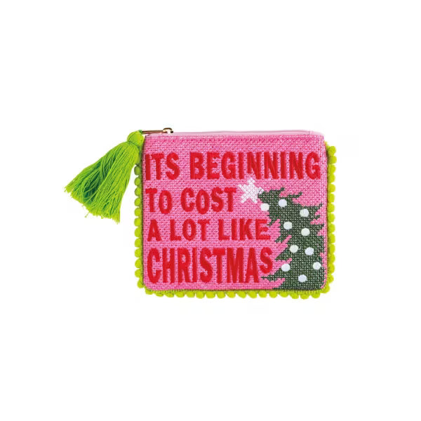 A small rectangular embroidered coin purse with a bright pink background, red text reading 'ITS BEGINNING TO COST A LOT LIKE CHRISTMAS,' a green Christmas tree motif, and a lime green tassel zipper pull, shown on a plain white background.