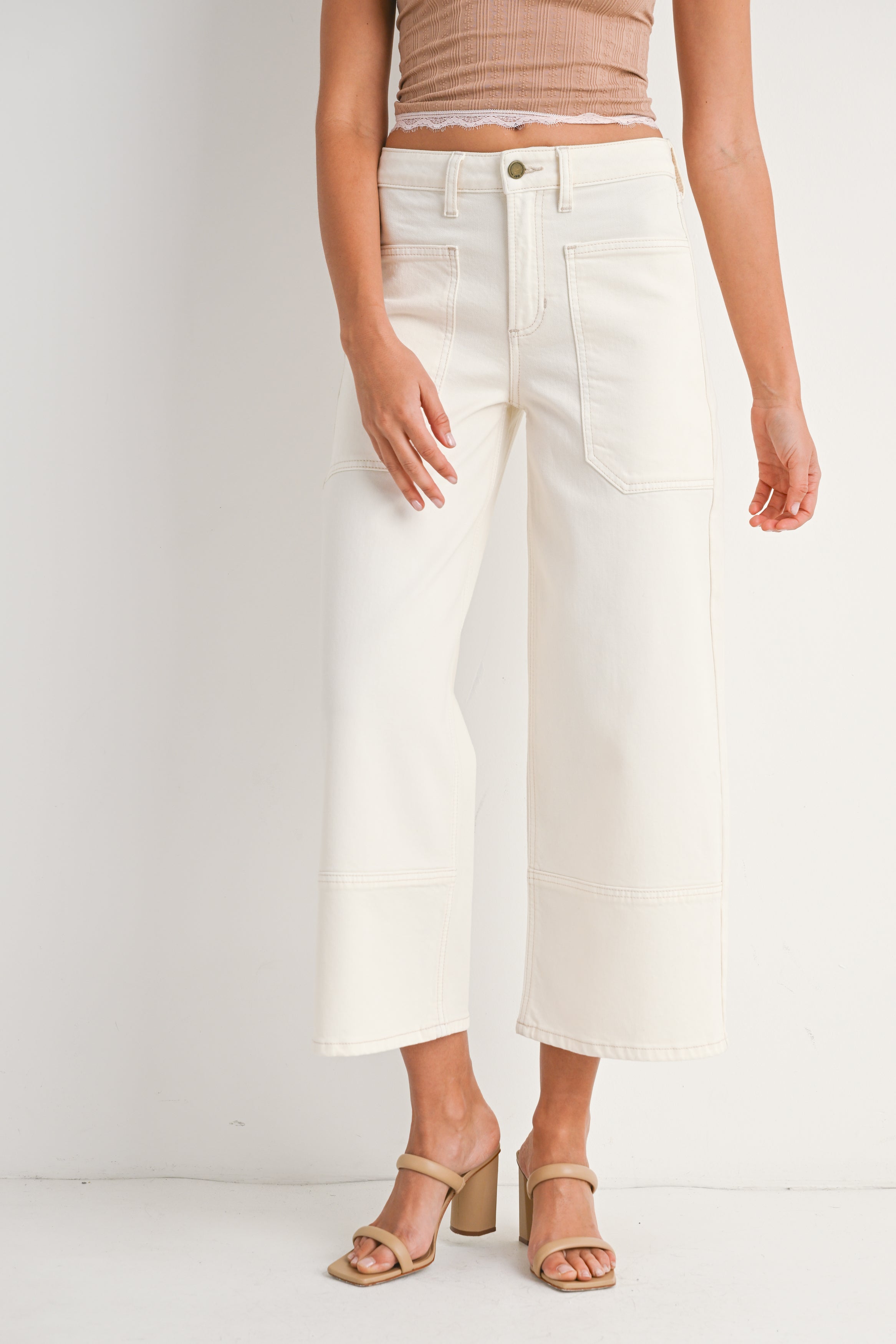 Person wearing white pants and a beige top on a plain background