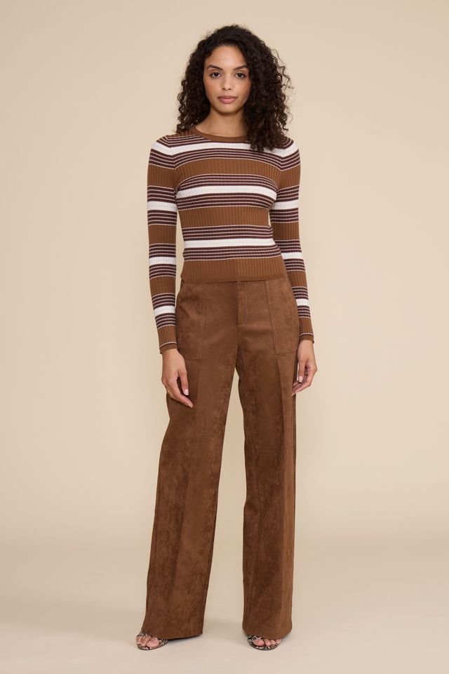 A woman modeling a brown and white striped long-sleeve knit top with matching brown wide-leg pants, standing against a solid beige studio background.