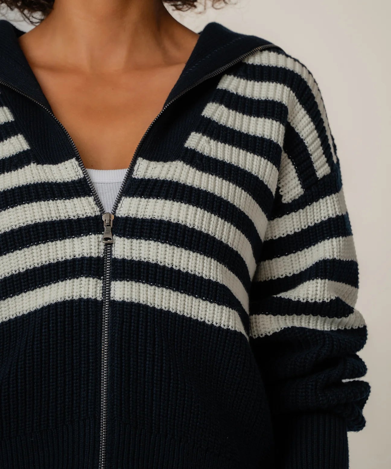 Close-up of a person wearing a black and white striped sweater with a zipper.