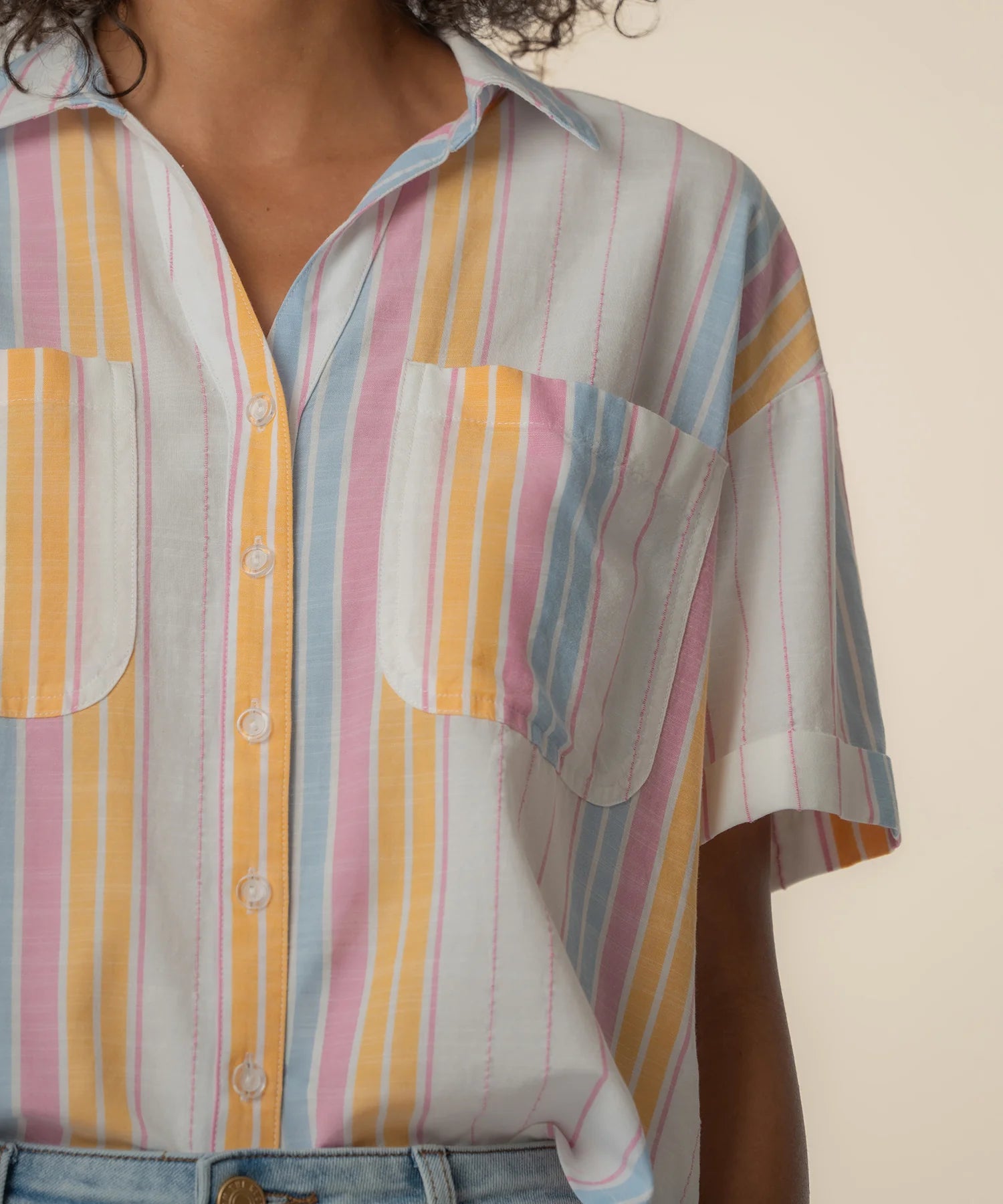 Pastel striped shirt worn by a person on a beige background