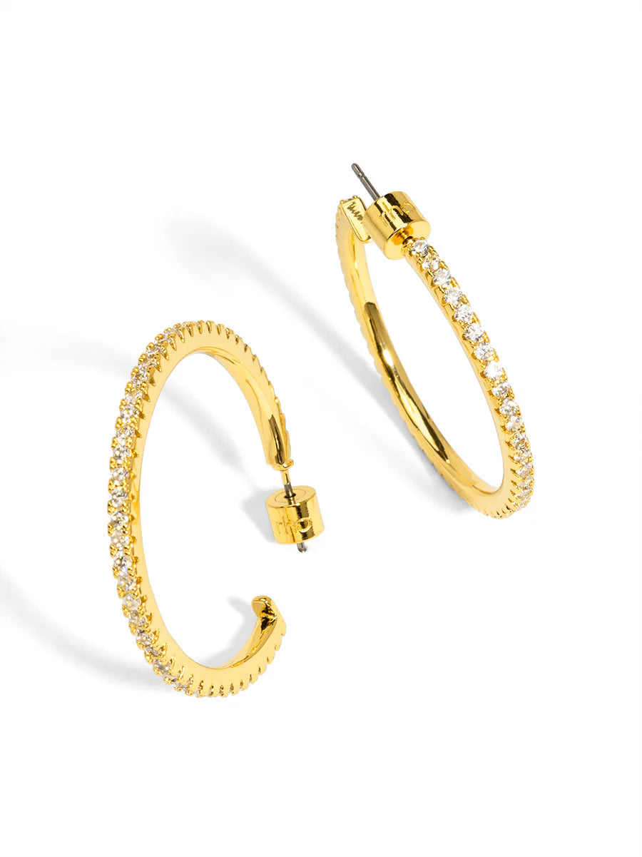 Gold hoop earrings with clear gemstones on a white background