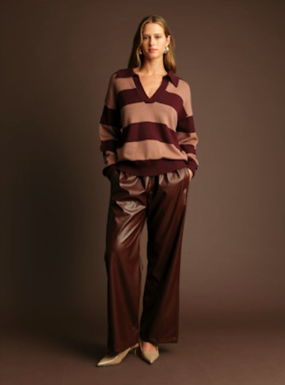 Woman wearing a striped sweater and wide-leg pants against a brown background
