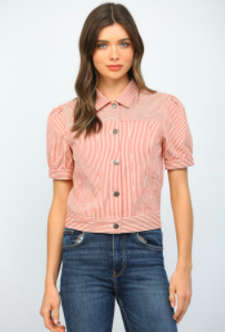 Woman wearing a pink ribbed blouse with short sleeves and blue jeans on a white background