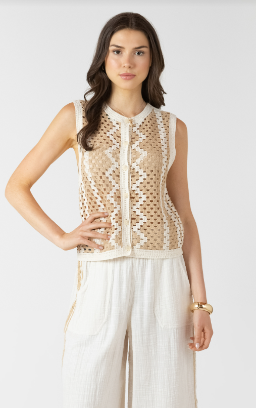 Woman wearing a beige sleeveless top with a pattern and white pants on a white background
