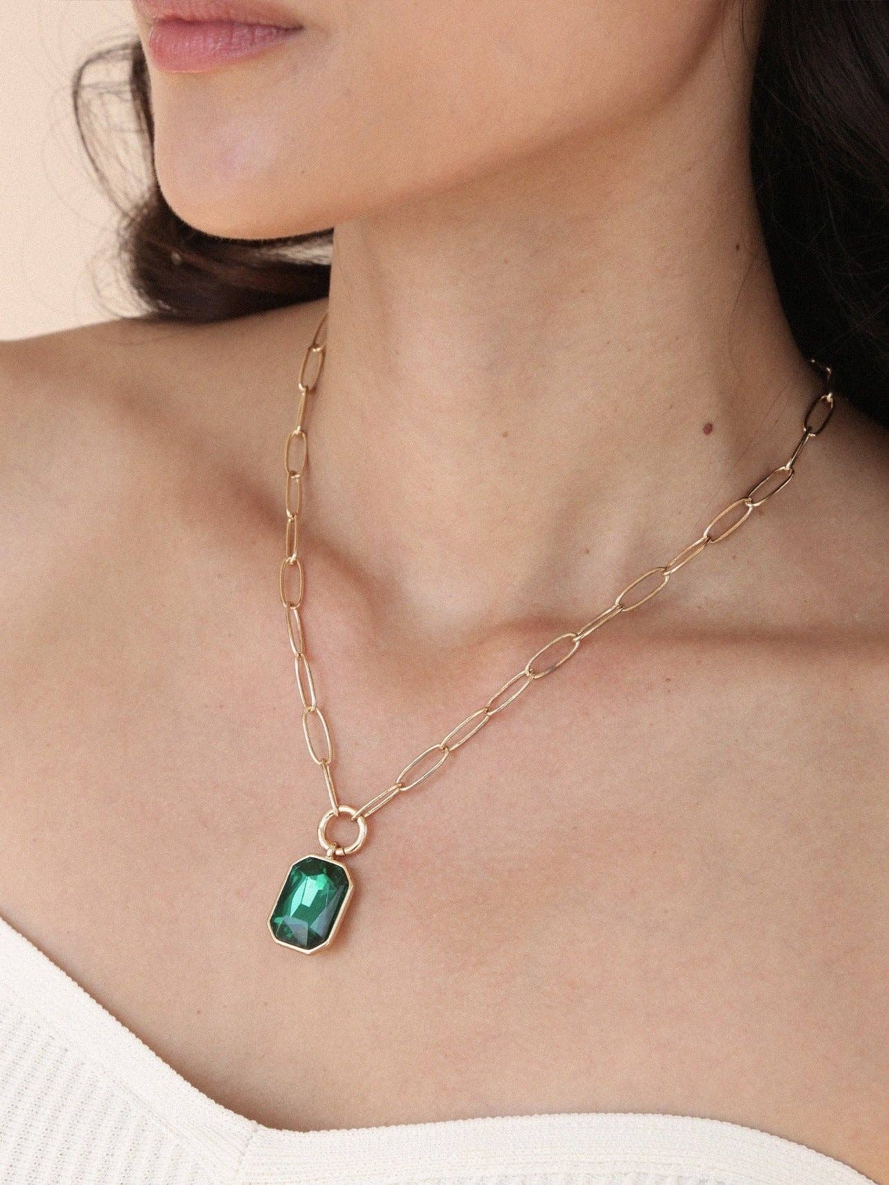 Necklace with a green pendant worn by a person on a neutral background