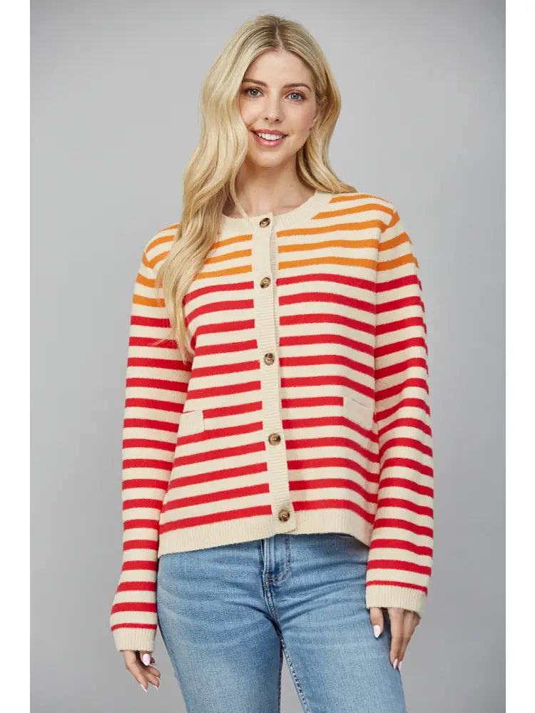 Woman wearing a striped sweater with red, yellow, and beige colors on a gray background