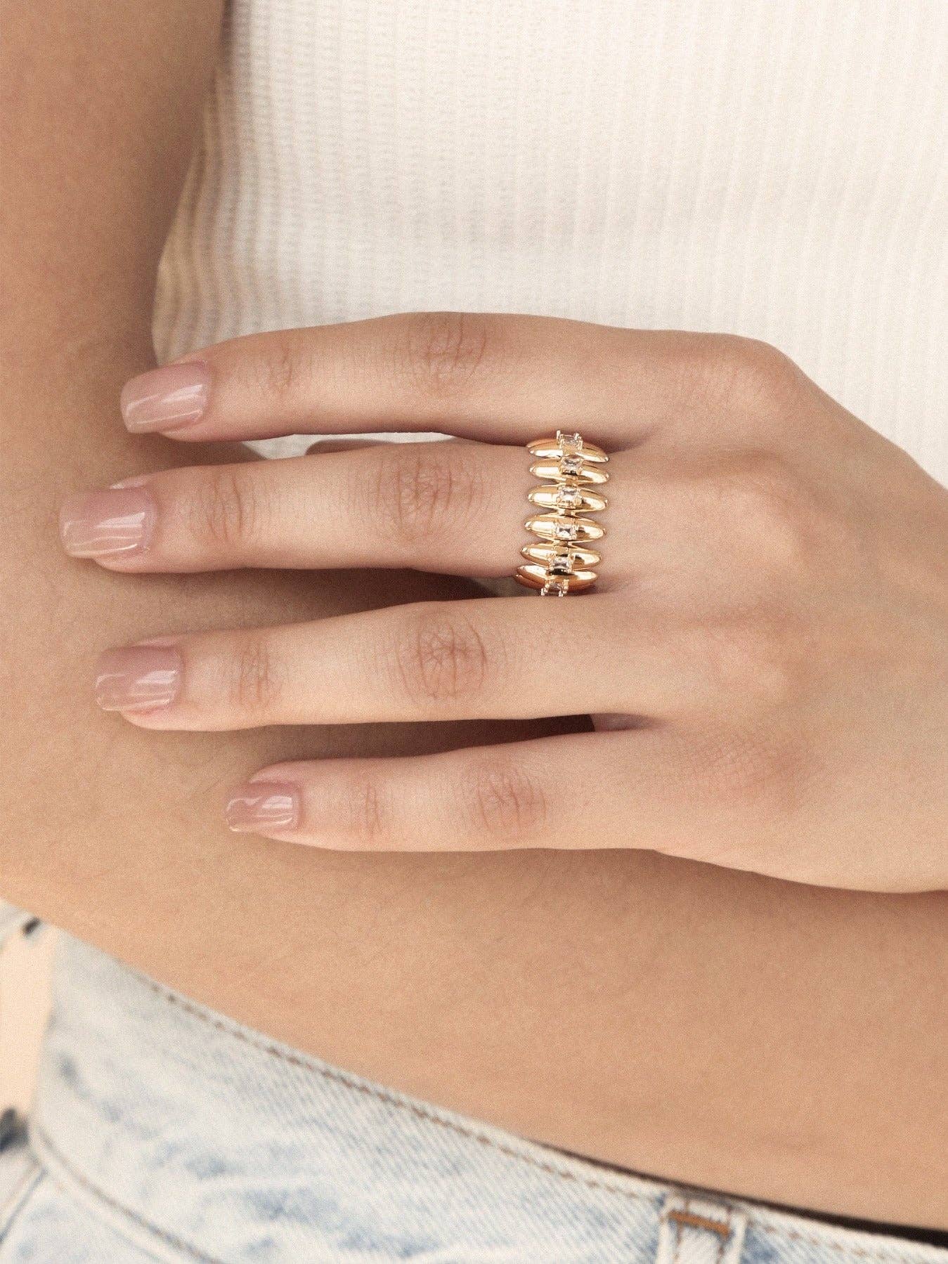 Hand wearing a gold ring with a blurred background