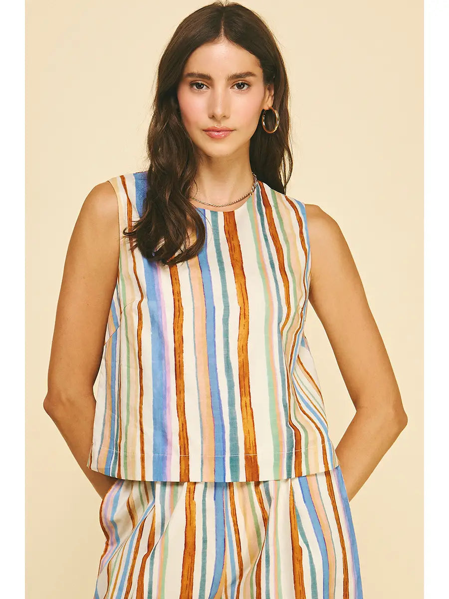 Woman wearing a sleeveless, multicolored striped top against a beige background