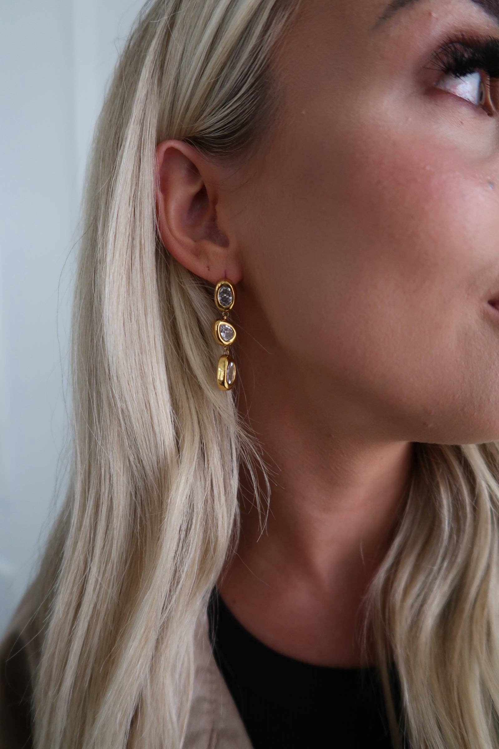 Close-up of a woman wearing gold earrings with a neutral background