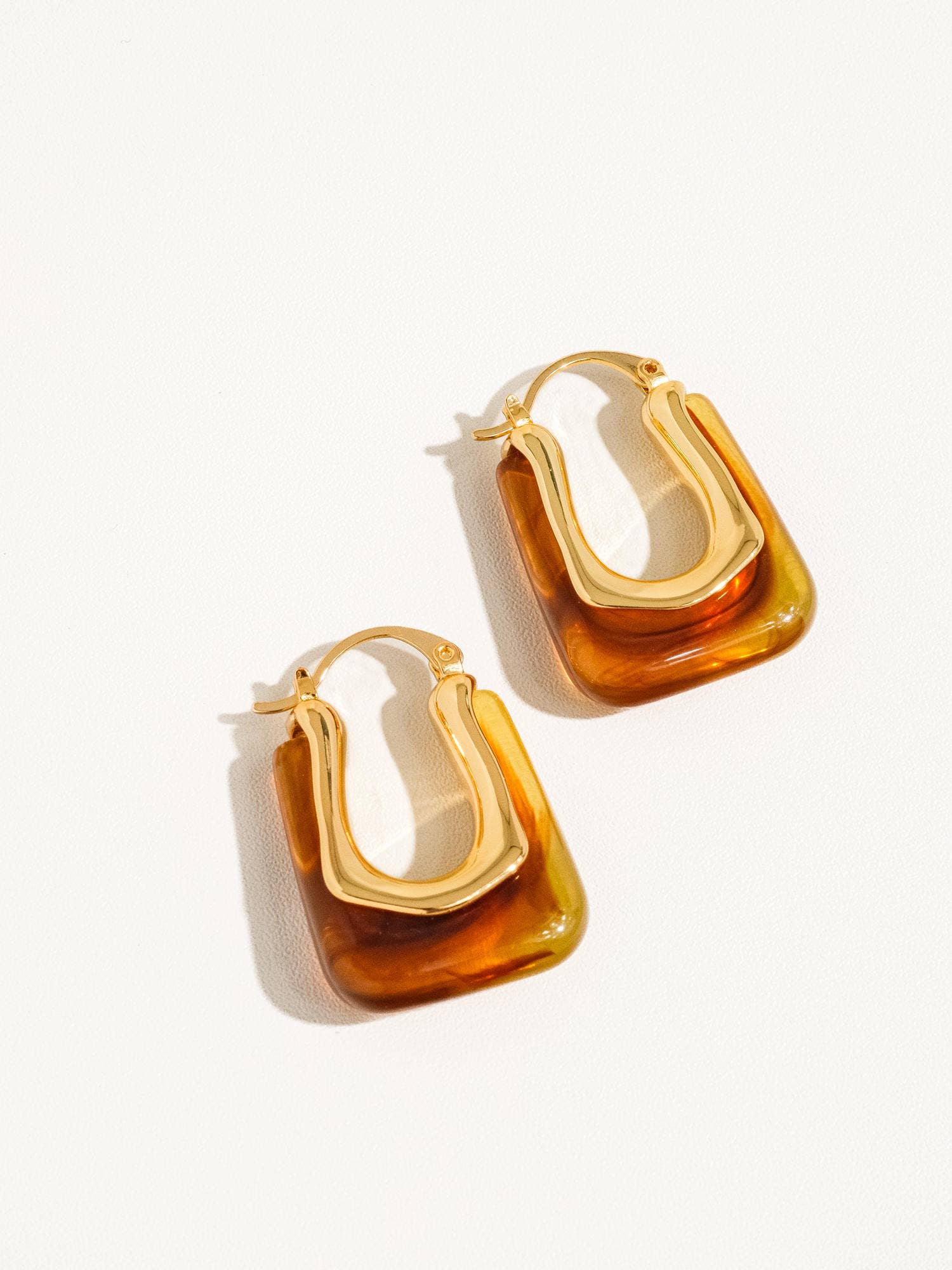 Pair of gold and amber hoop earrings on a white background