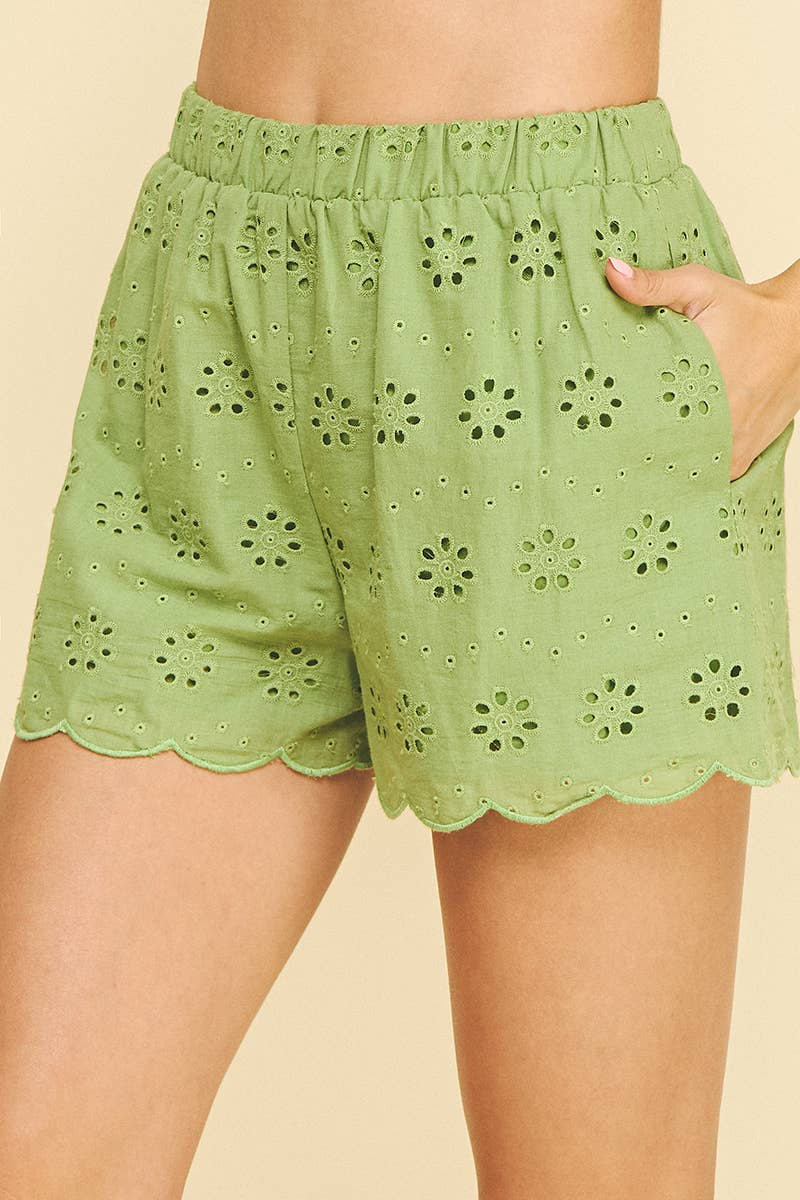 Green eyelet shorts worn by a person on a beige background