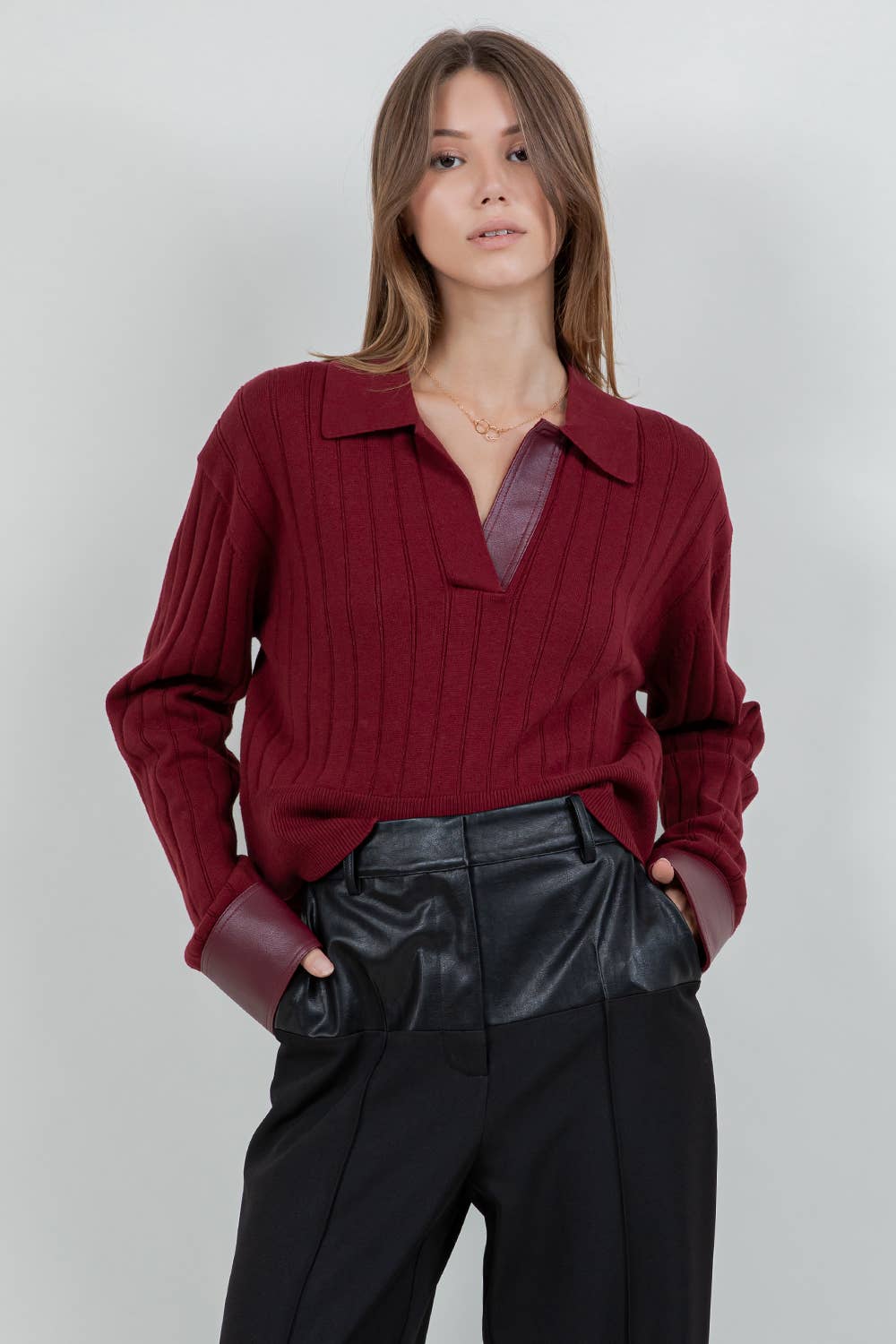 Woman wearing a red sweater and black pants against a plain background