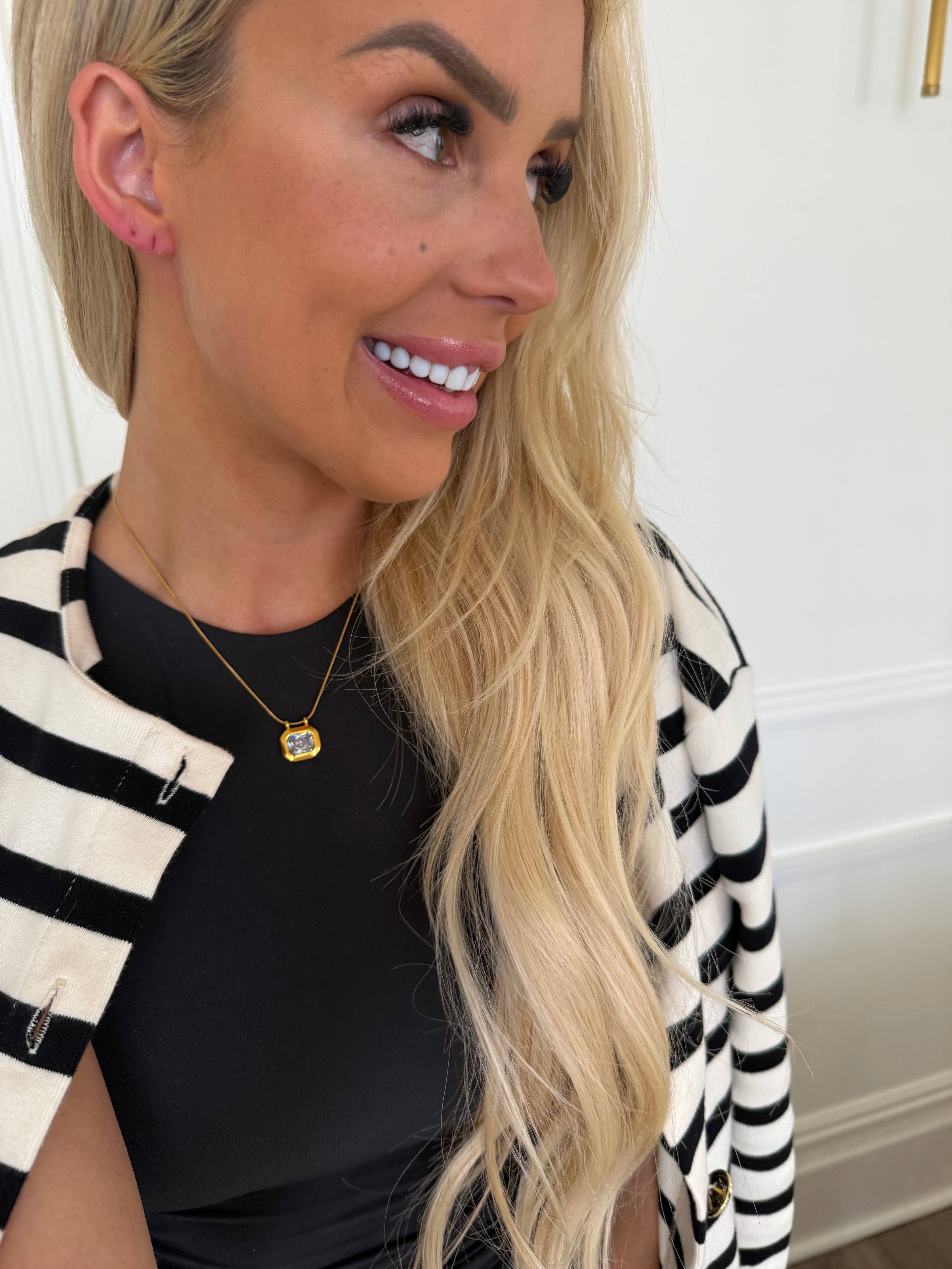 Woman wearing a black top and striped cardigan with a white background