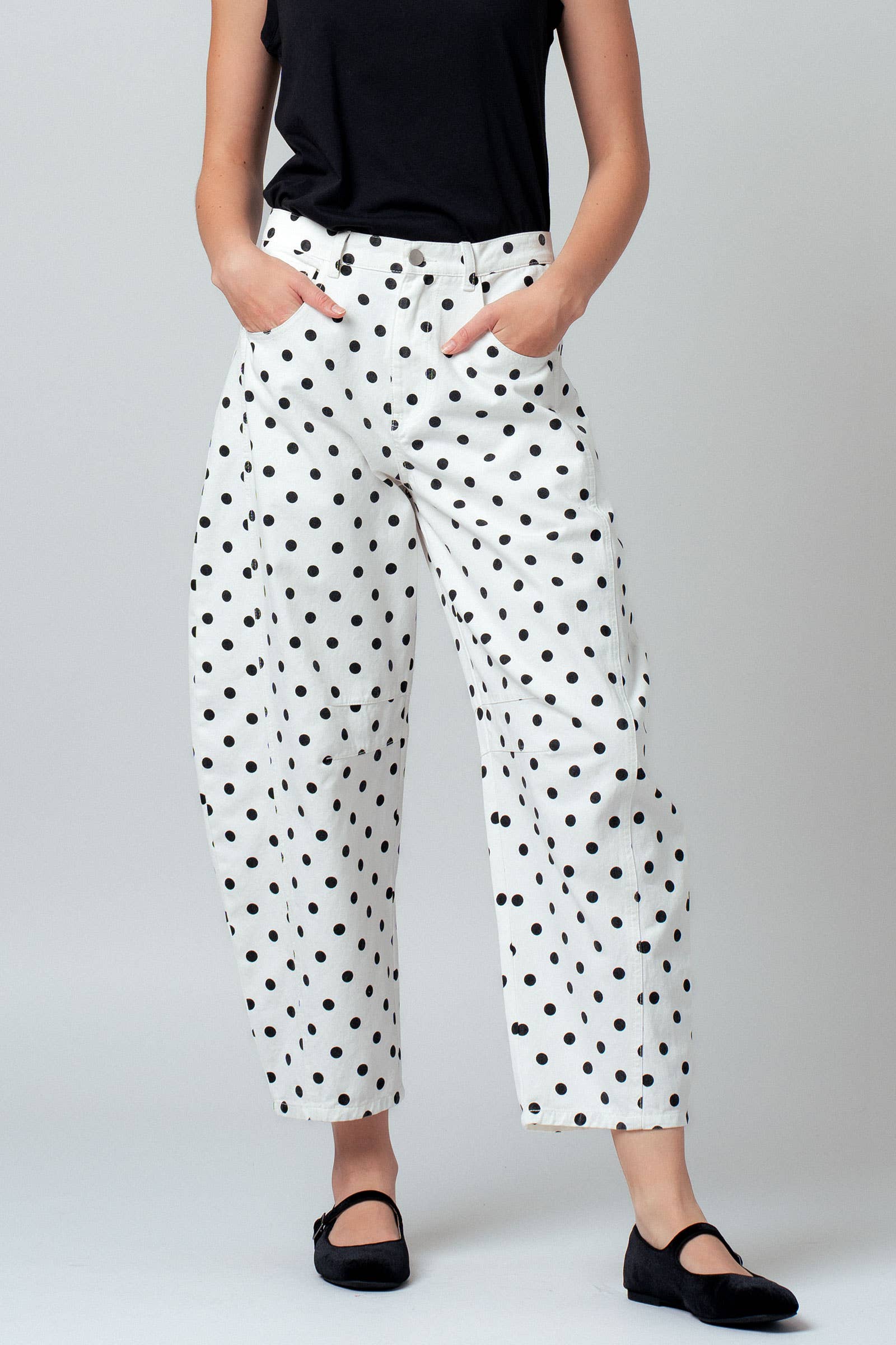 White pants with black polka dots worn by a person on a plain background