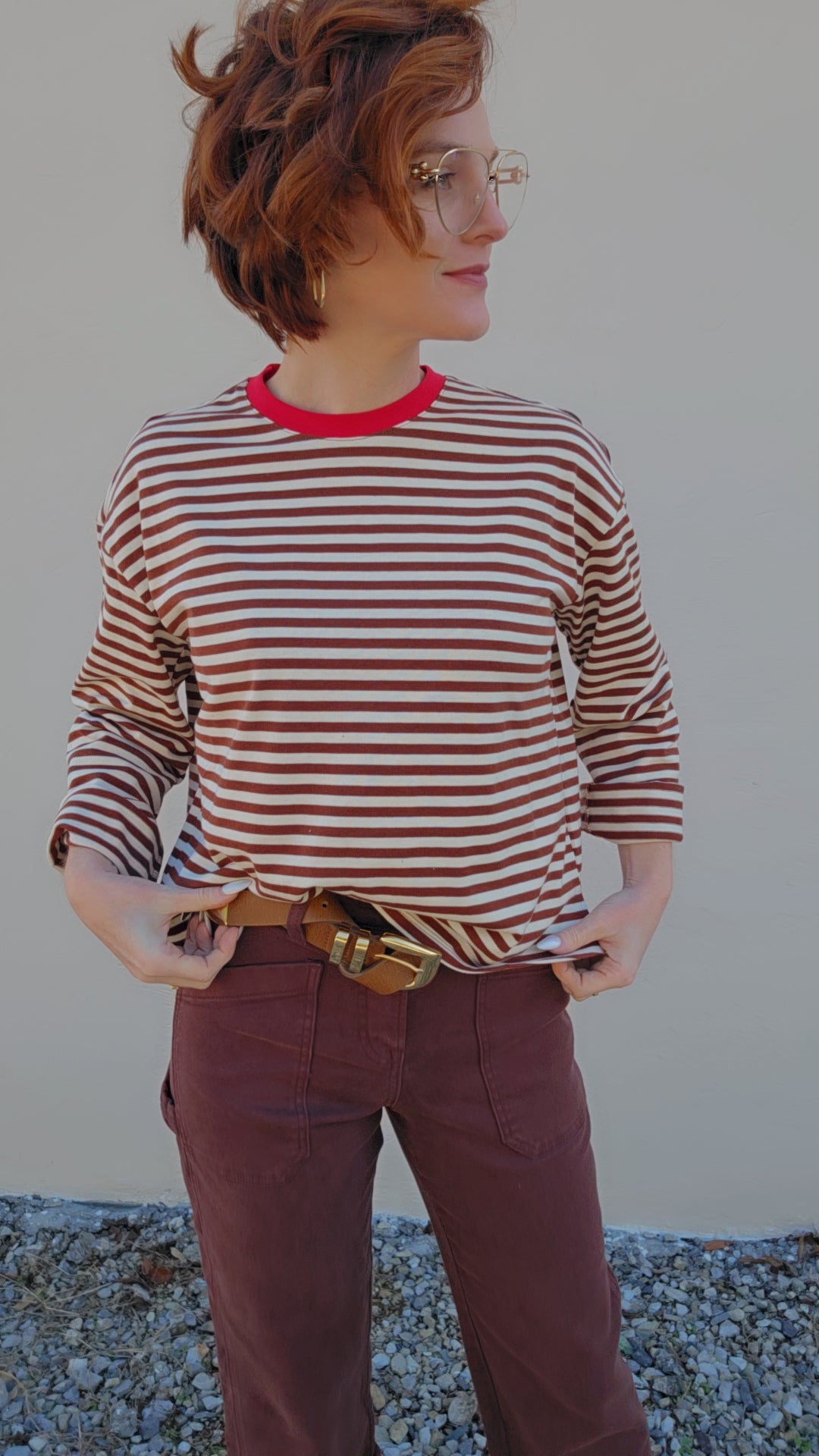 Person wearing a red and white striped shirt with maroon pants against a plain background