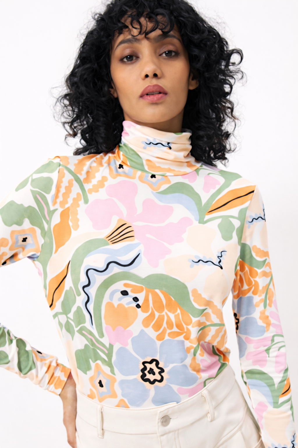 Woman wearing a colorful floral turtleneck sweater against a white background