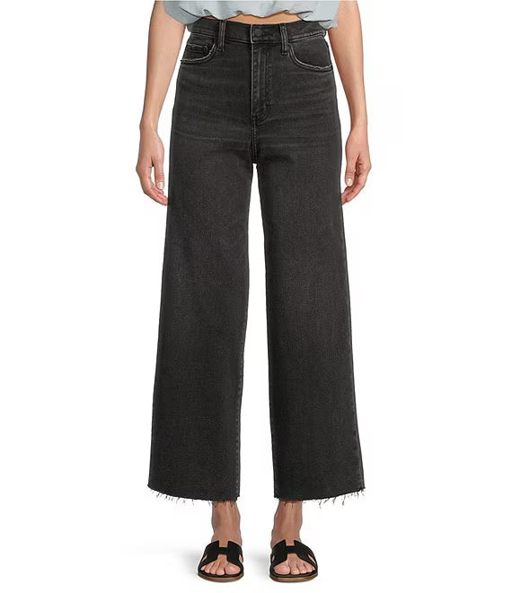 Person wearing black wide-leg jeans on a white background