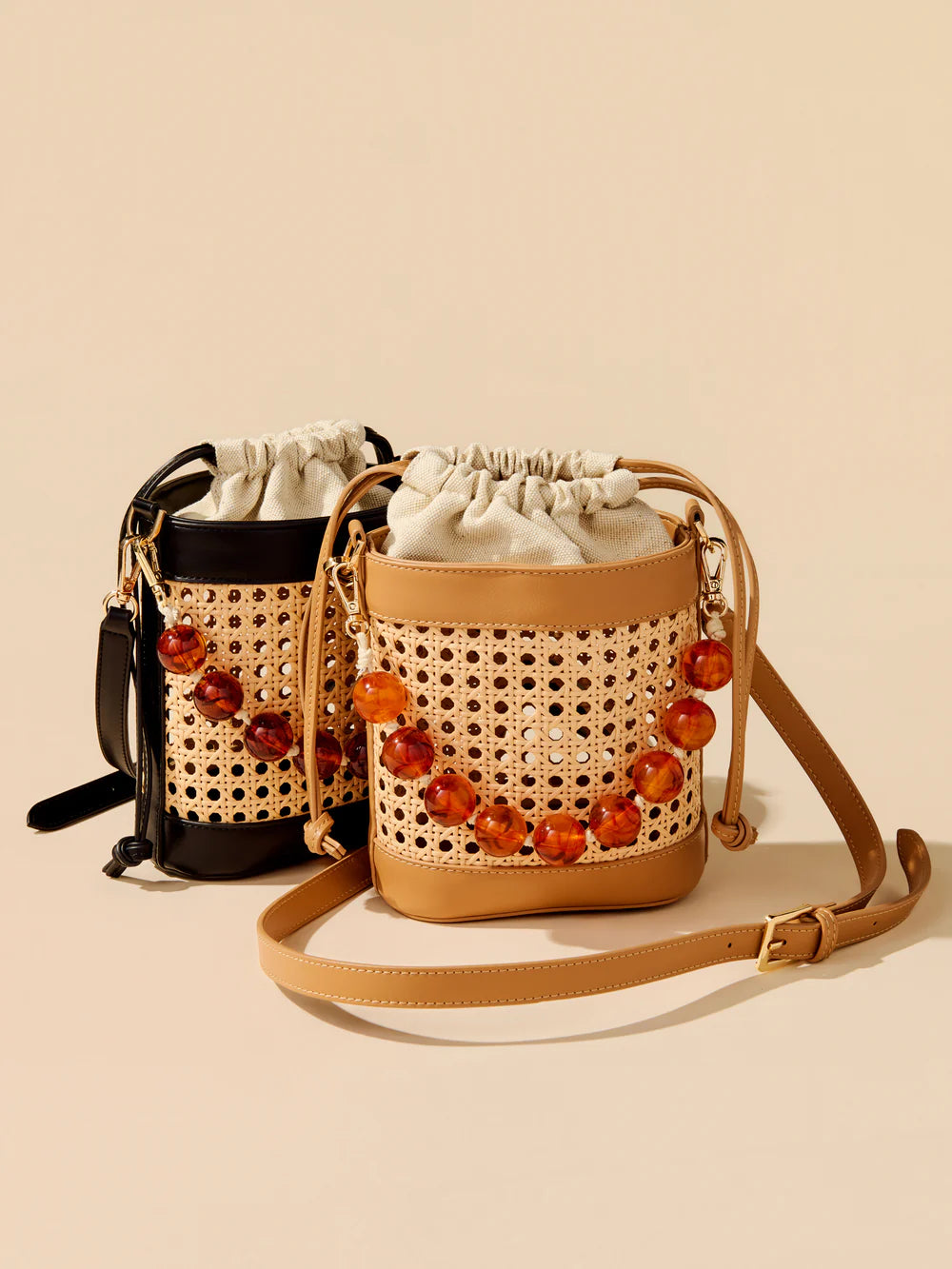 Two woven handbags with decorative beads on a beige background