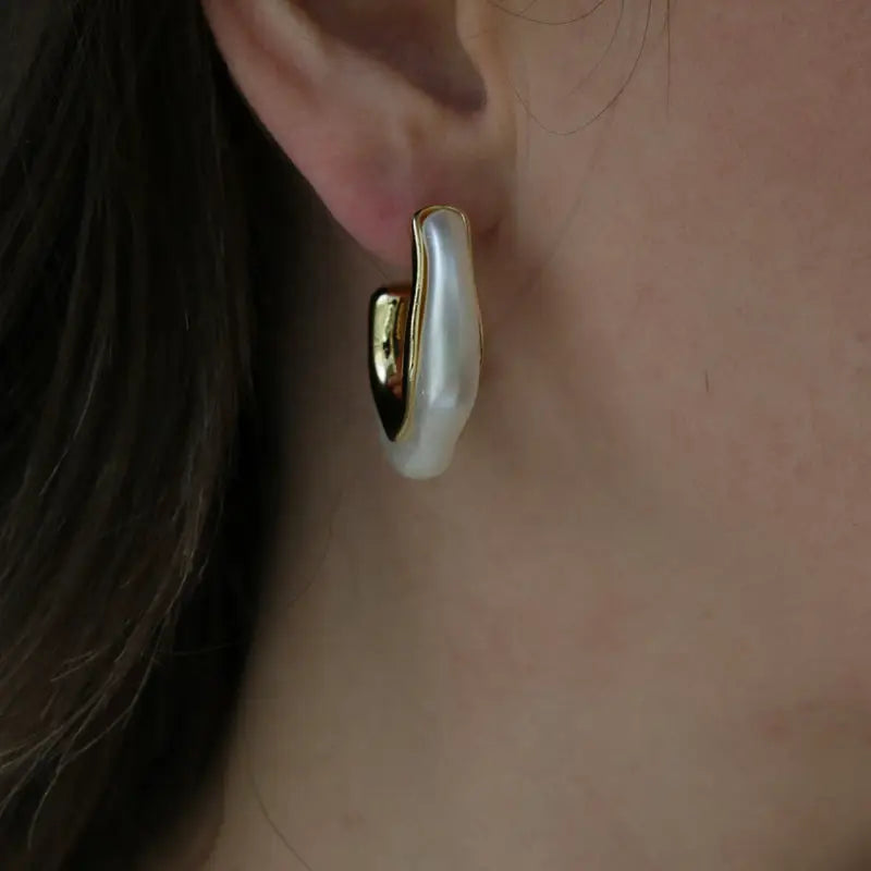 Pearl earring worn on an ear with a neutral background