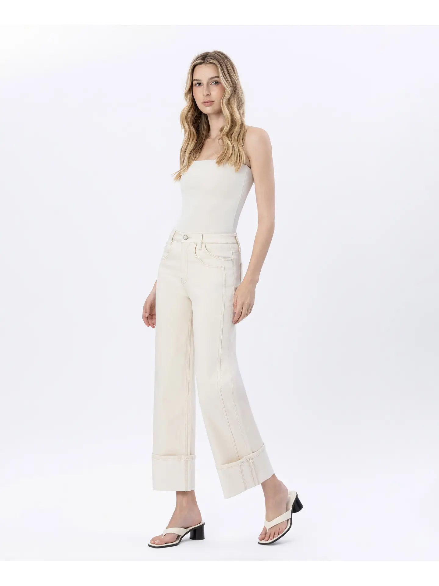 Woman wearing a white strapless top and pants on a white background