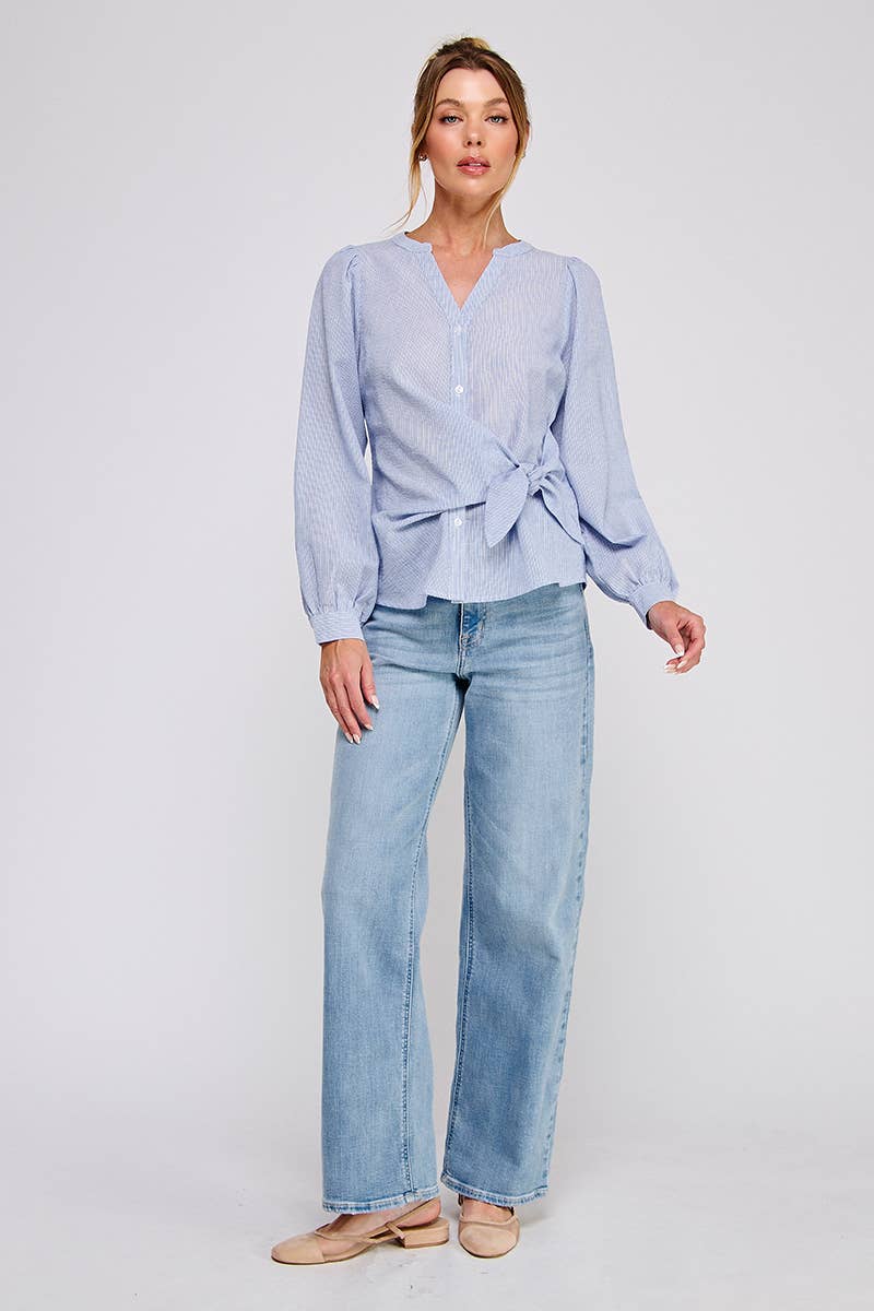 Woman wearing a light blue striped blouse and jeans on a white background