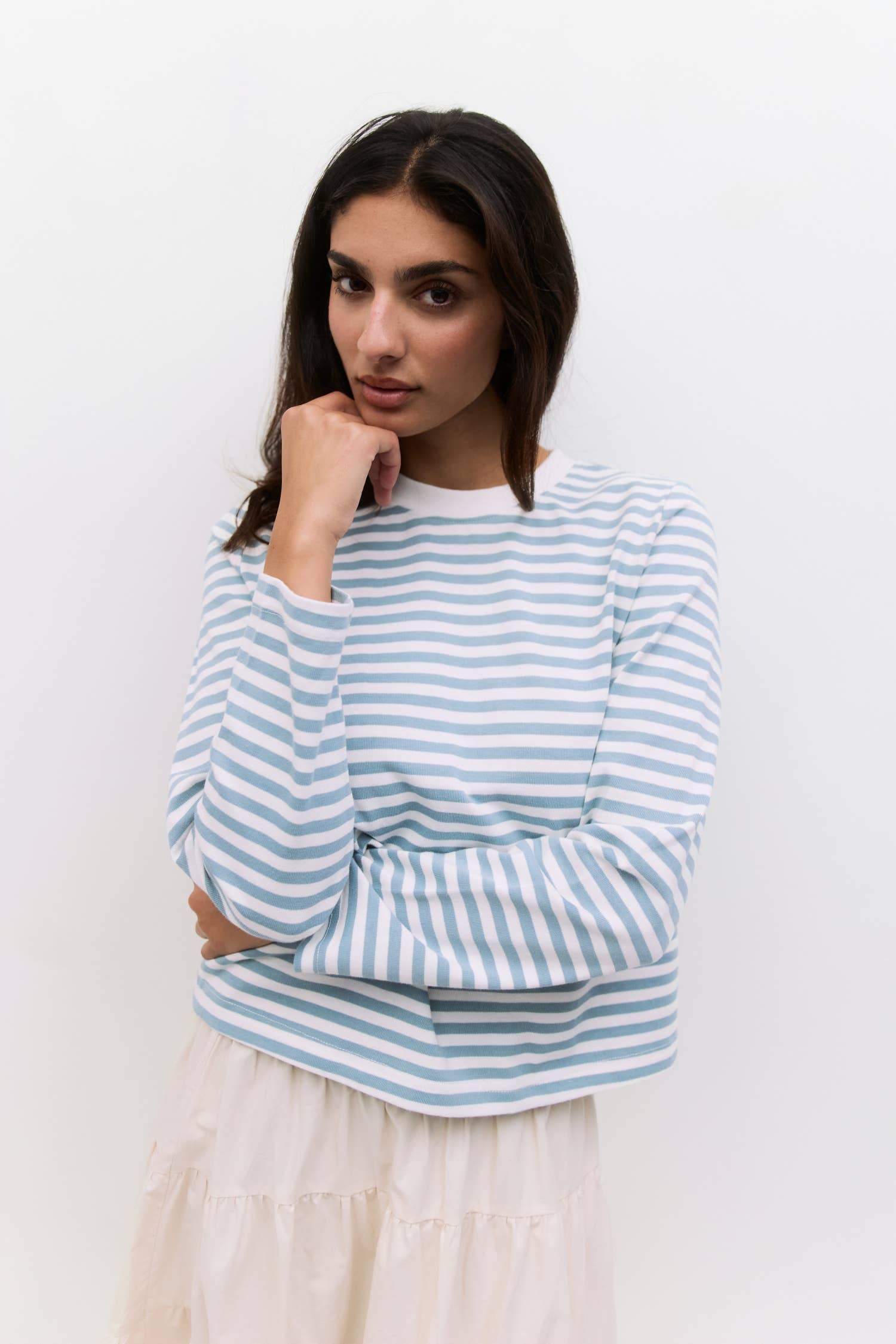 Woman wearing a blue and white striped sweater against a plain background