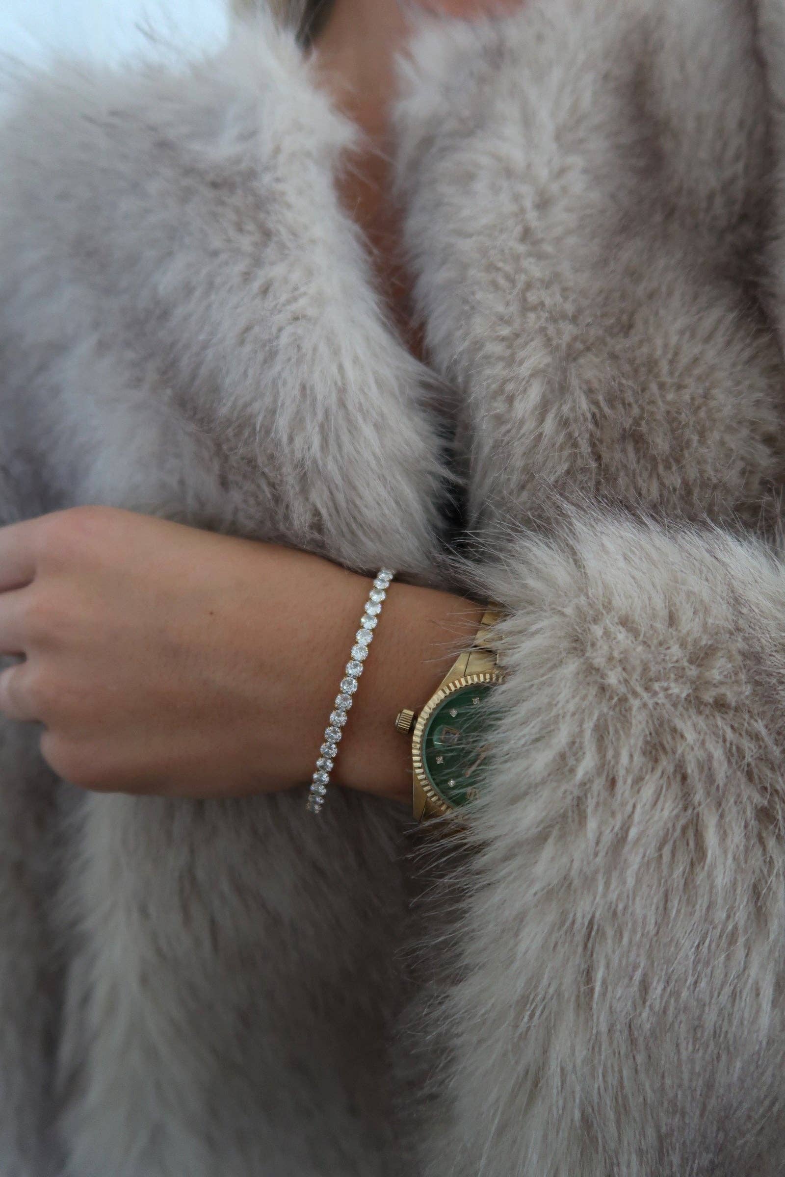 Person wearing a gold watch and bracelet on a fur coat
