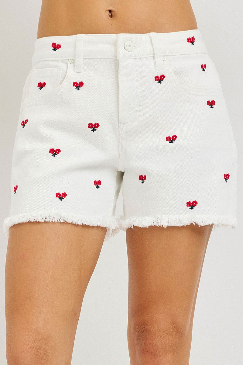 White shorts with red floral embroidery on a plain background