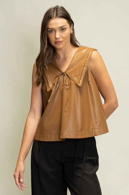 Woman wearing a brown leather top against a plain background