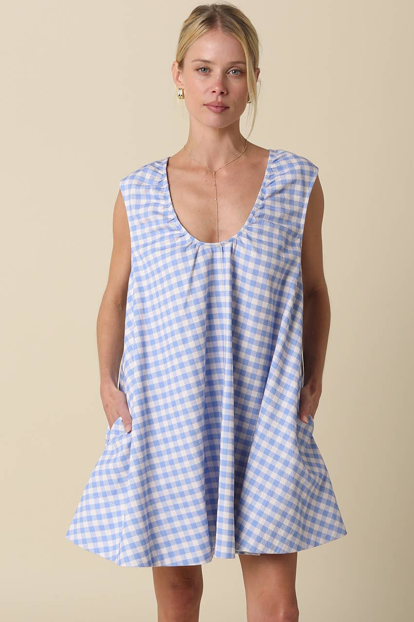 Woman wearing a blue and white checkered dress against a beige background