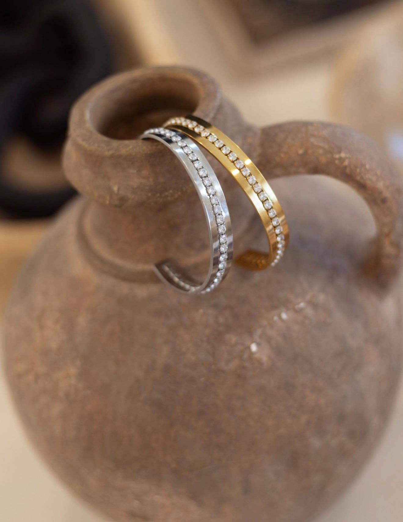 Two rings, one gold and one silver, on a textured surface.