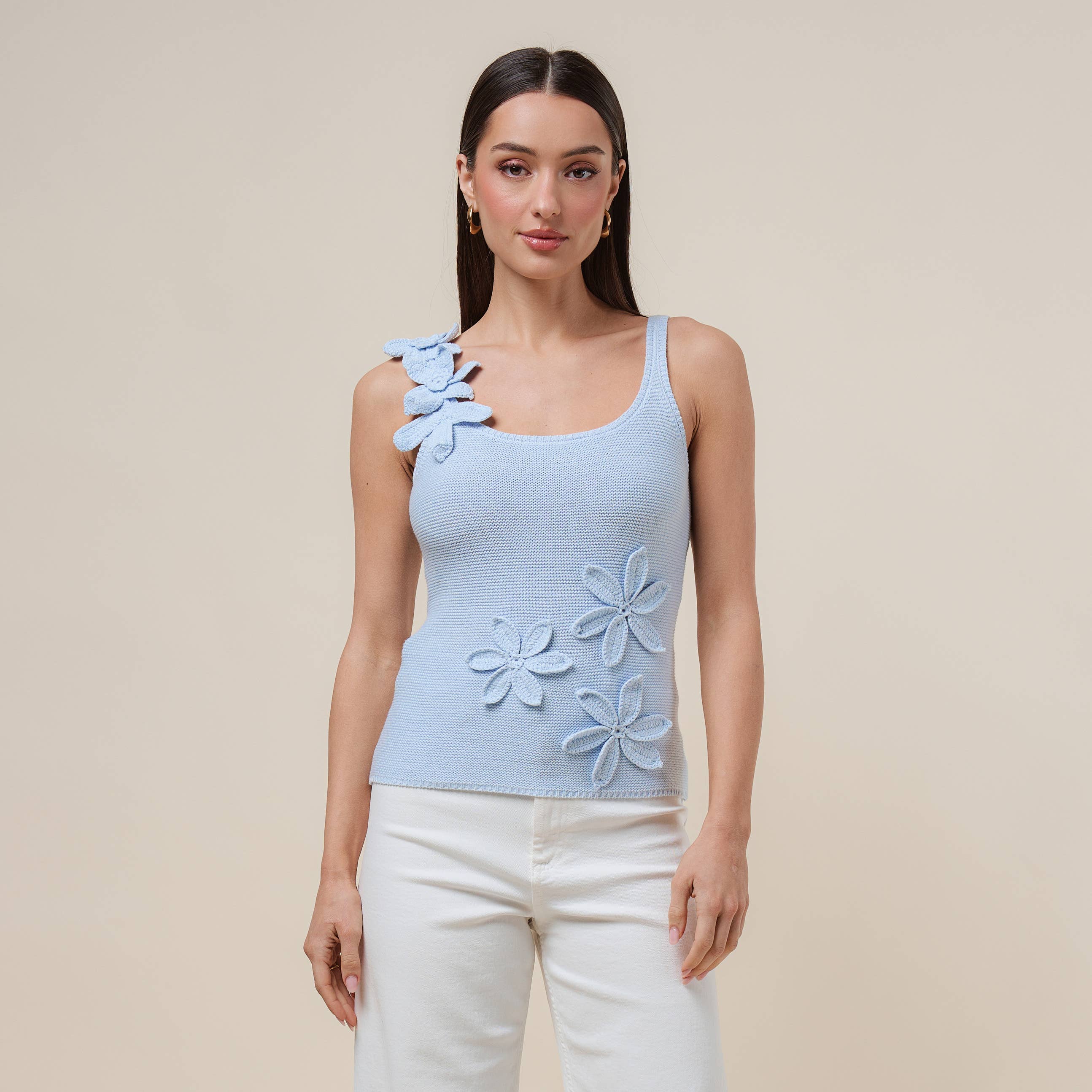 Woman wearing a light blue sleeveless top with floral designs on a beige background