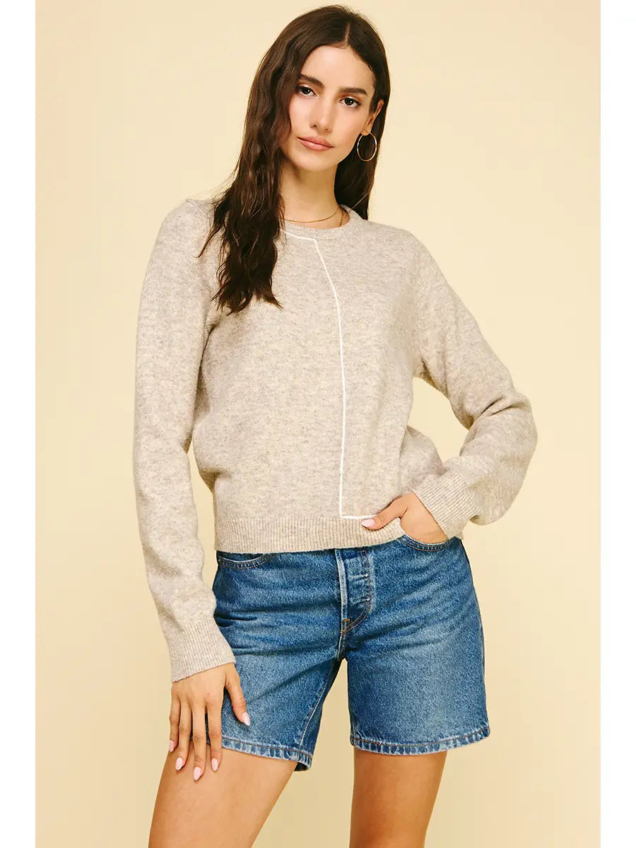 Woman wearing a beige sweater and blue denim shorts on a beige background