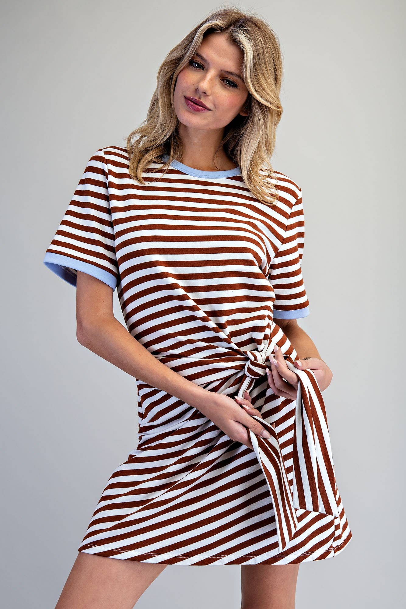 Woman wearing a brown and white striped dress against a gray background