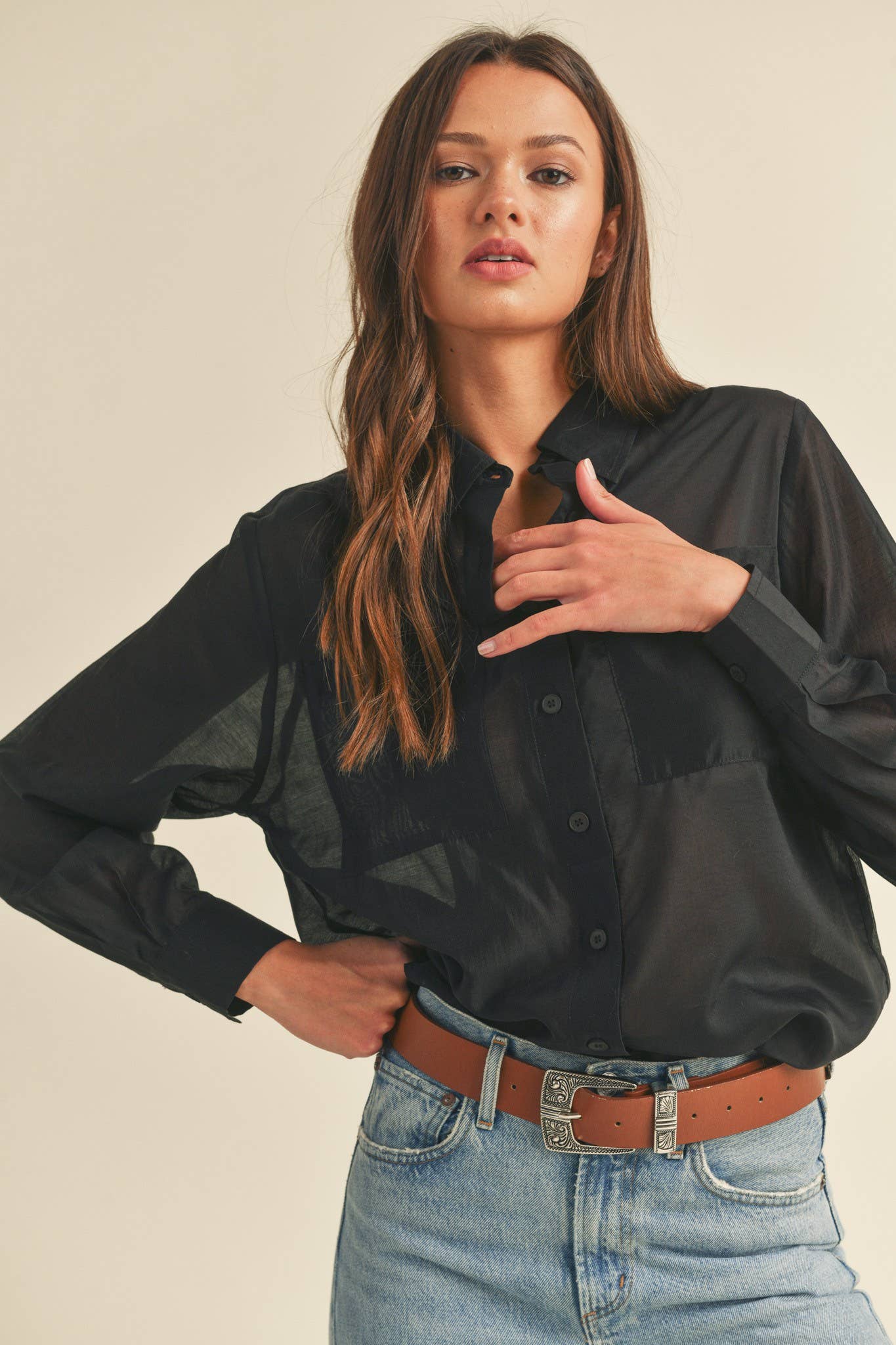 Woman wearing a black shirt and blue jeans with a beige background