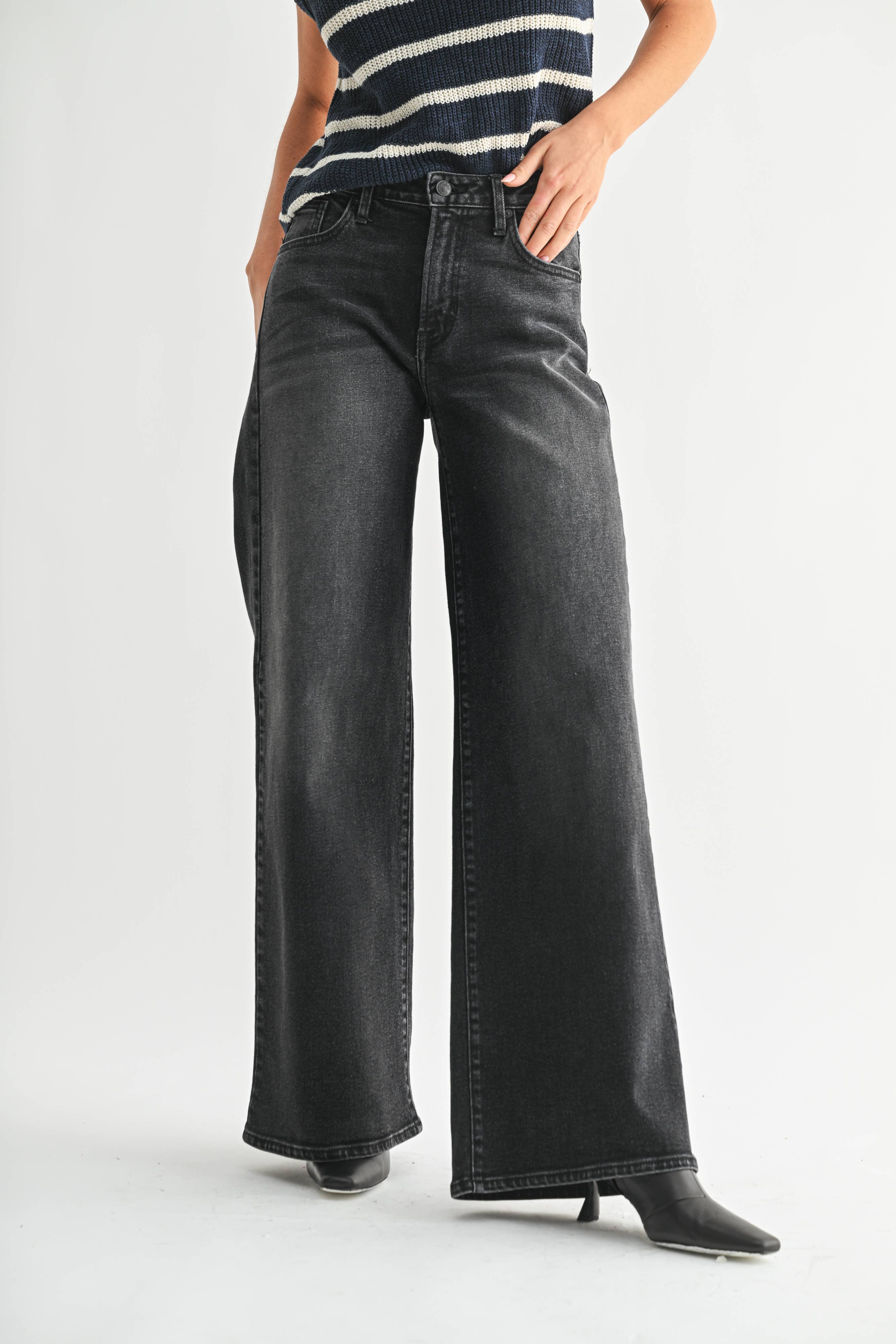 Person wearing black wide-leg jeans and a striped shirt on a white background