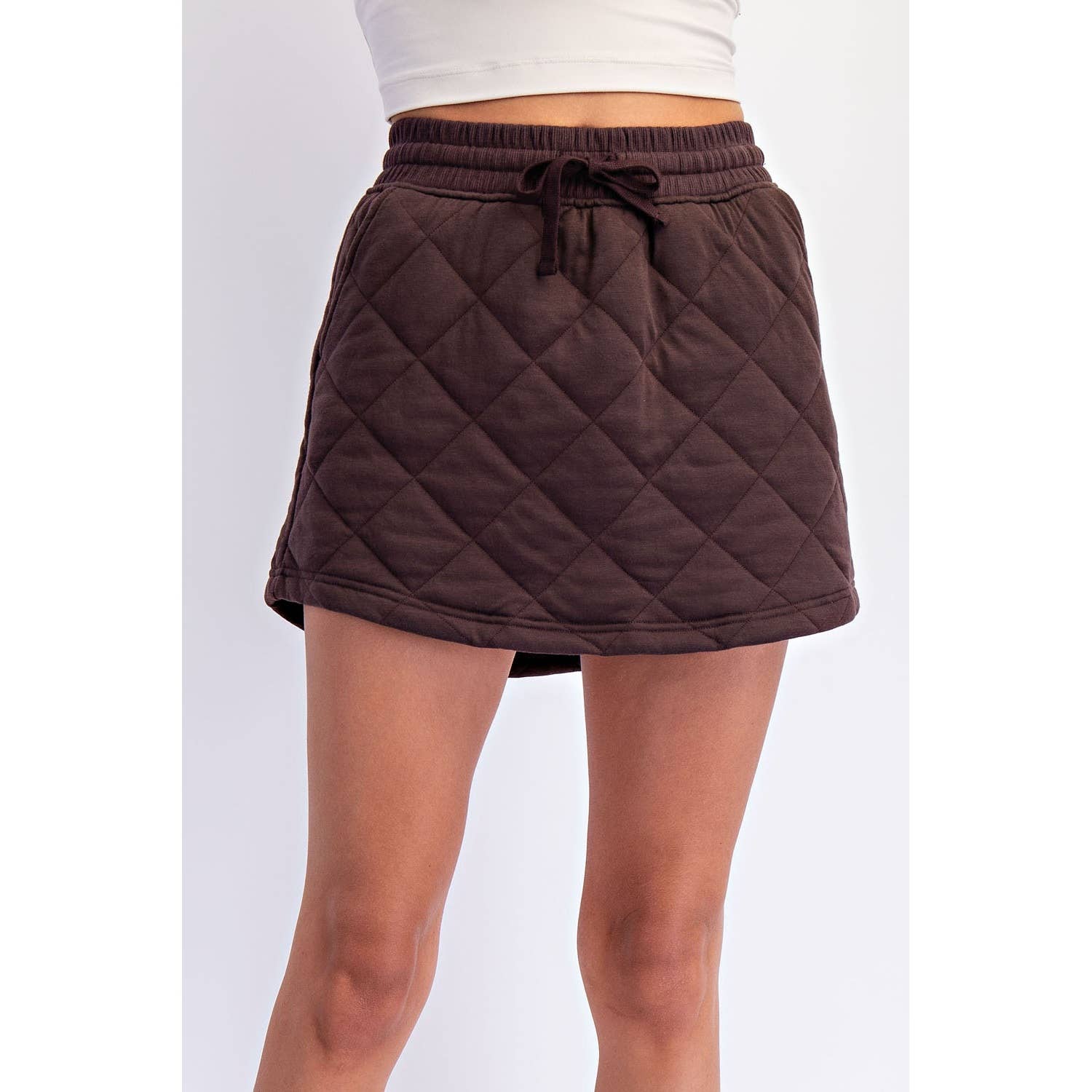 Brown quilted skirt worn by a person on a white background